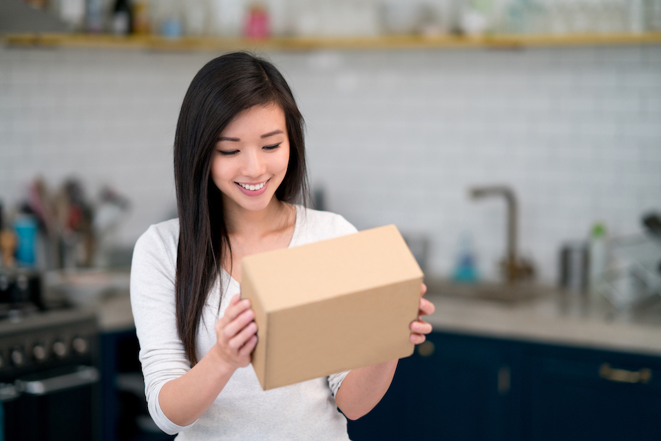 A woman holding a package from an online ecommerce subscription service.