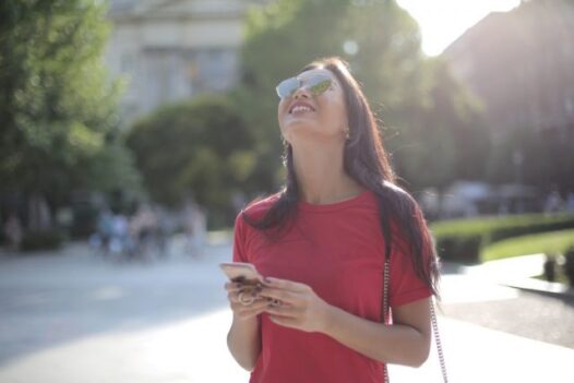 a woman smiles while holding her smartphone