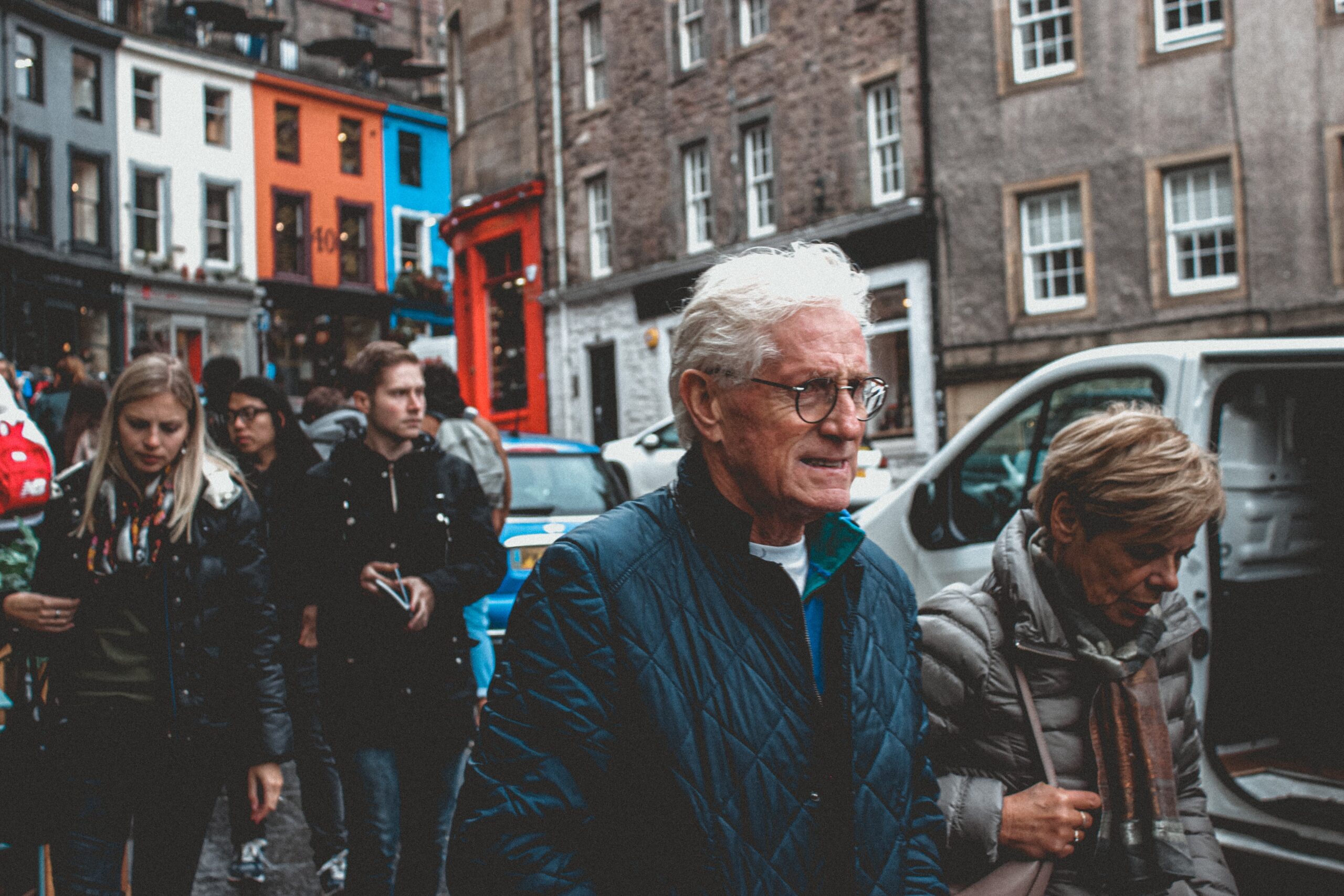 an older couple walk together through a crowded european streeet