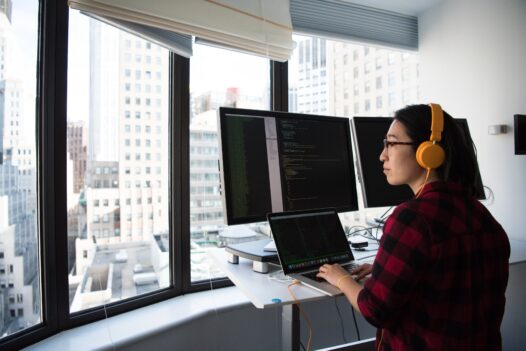 Woman programmer codes at a standing desk overlooking the city
