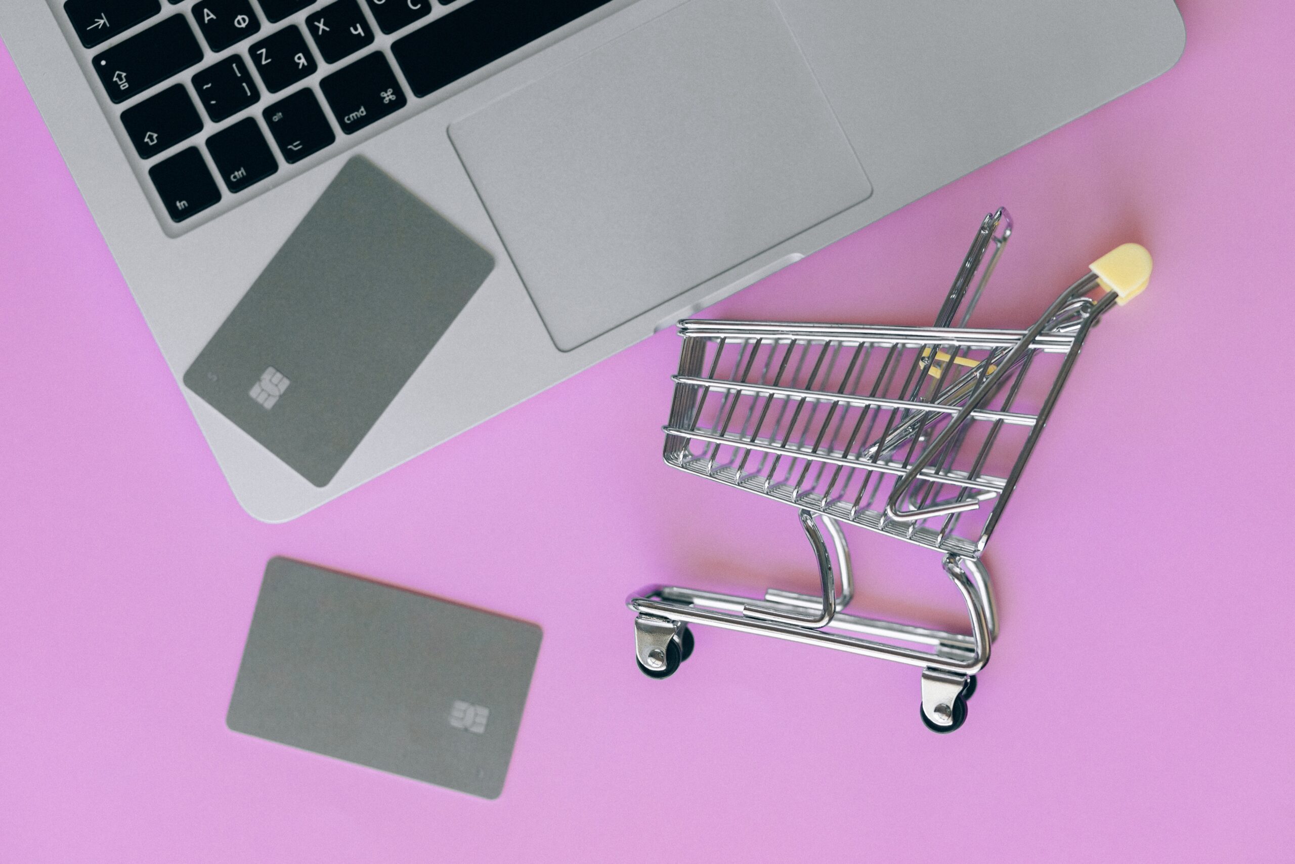 Credit cards and a shopping cart lie next to a laptop