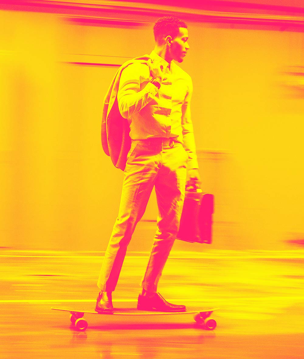 Young man riding a skateboard with a bag in his hand.