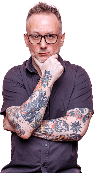 Man wearing glasses holds face with heavily tattooed arms