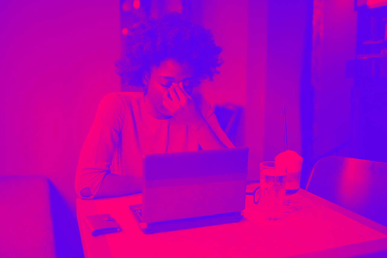 A woman holds her head in front of a laptop, representing eCommerce Pain Points