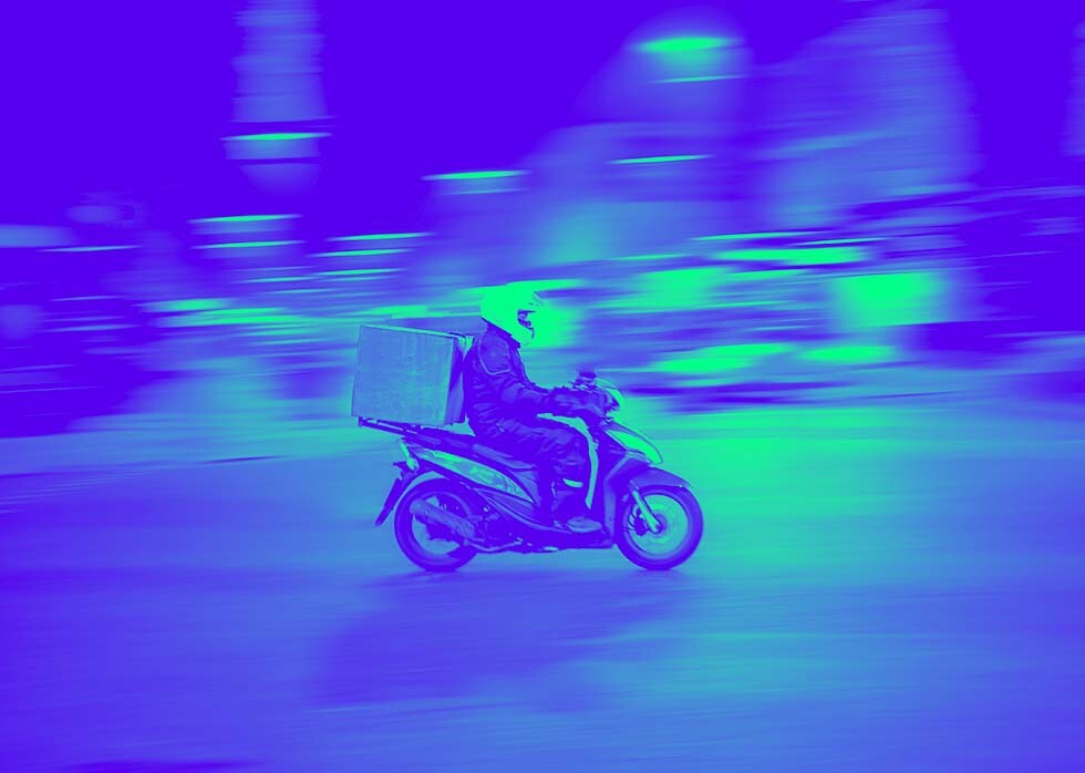 A courier rides a scooter, representing how to pay gig-economy workers across the globe