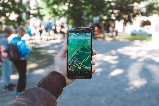 A person uses their phone to view an augmented reality scene in a park.