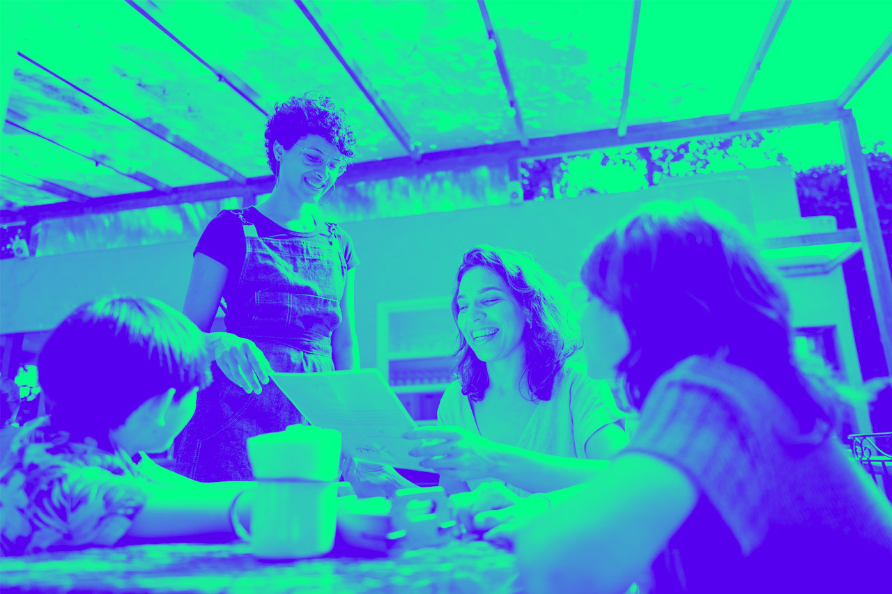 Waitress showing menu to mother and two children in cafe