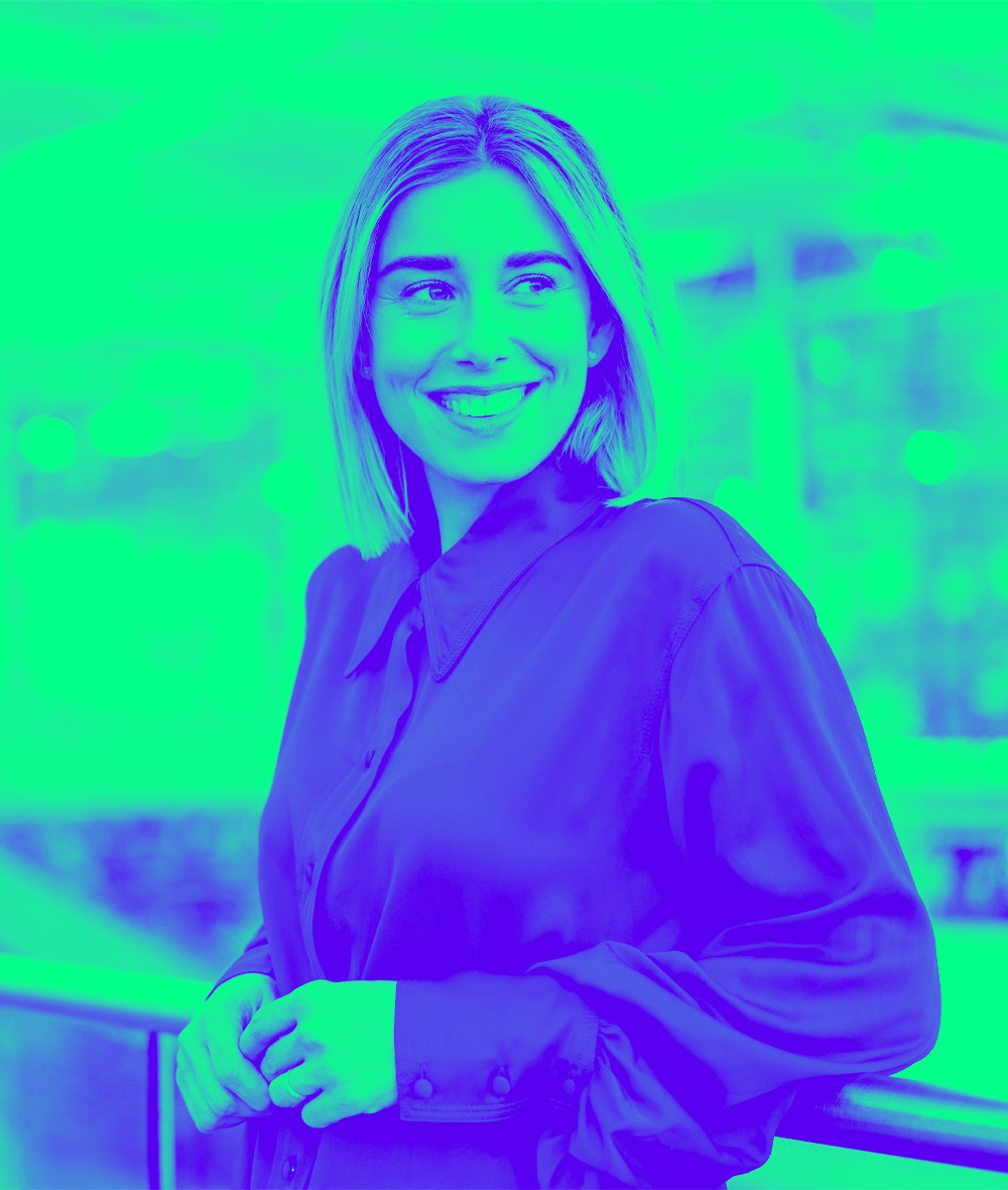 Smiling young businesswoman standing at a railing looking around