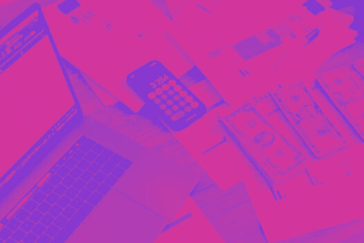 A laptop open with papers, stacks of bills, and calculator next to it