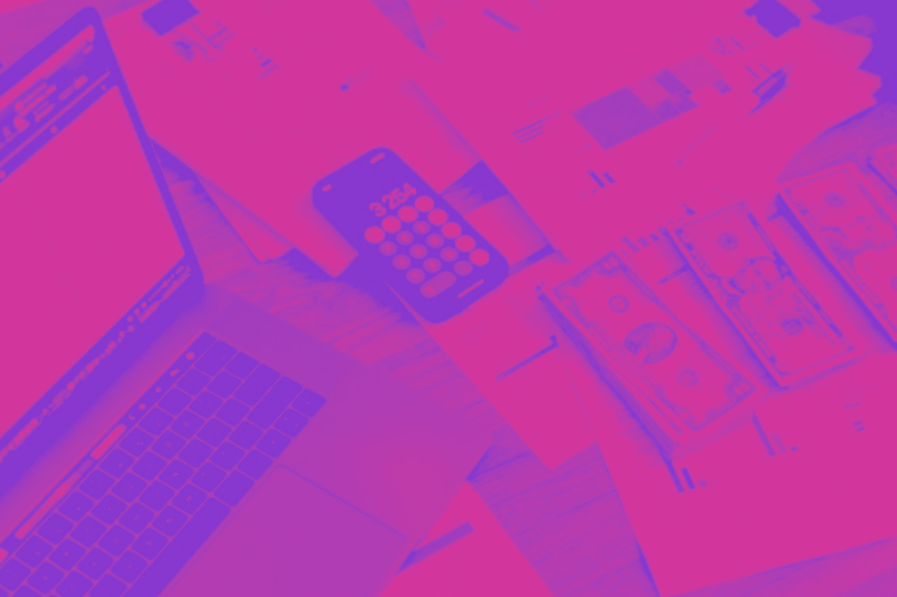 A laptop open with papers, stacks of bills, and calculator next to it