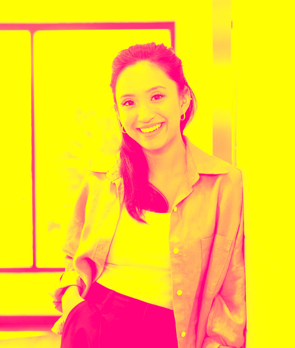 A woman is standing and smiling.