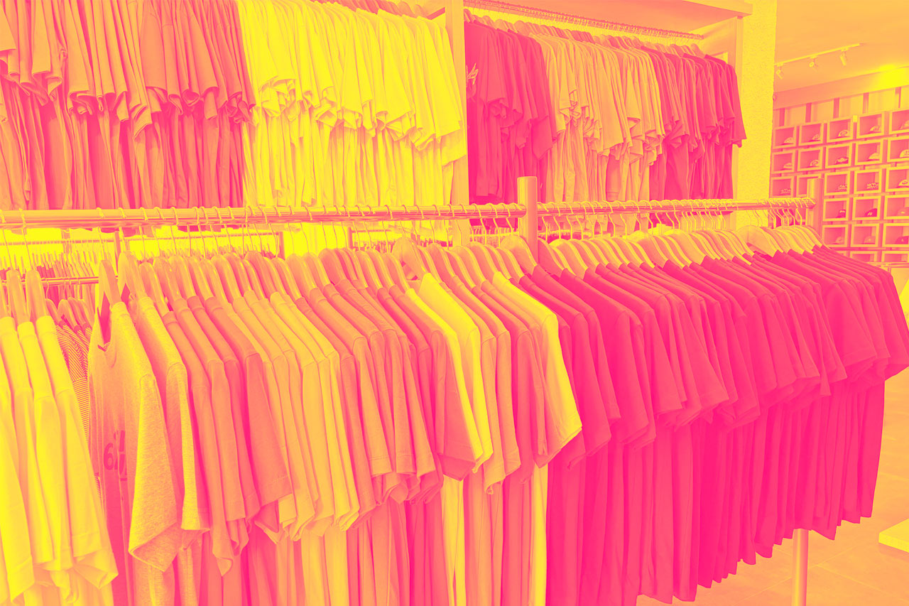 A clothing store display various t-shirts in a wide spectrum of colors