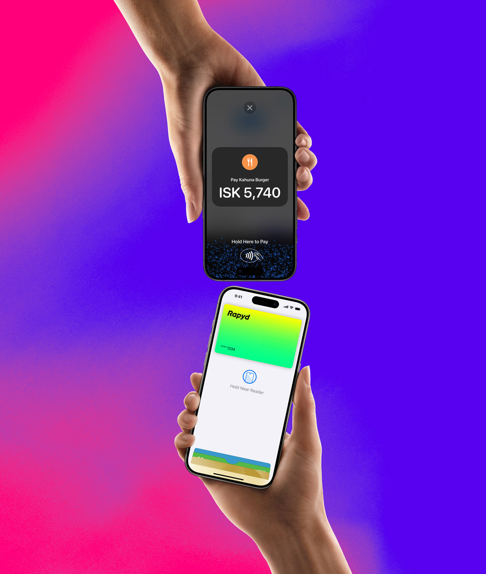 A hand holding an iPhone with a Rapyd credit card is about to pay on an iPhone that has a hold here to pay screen on it.